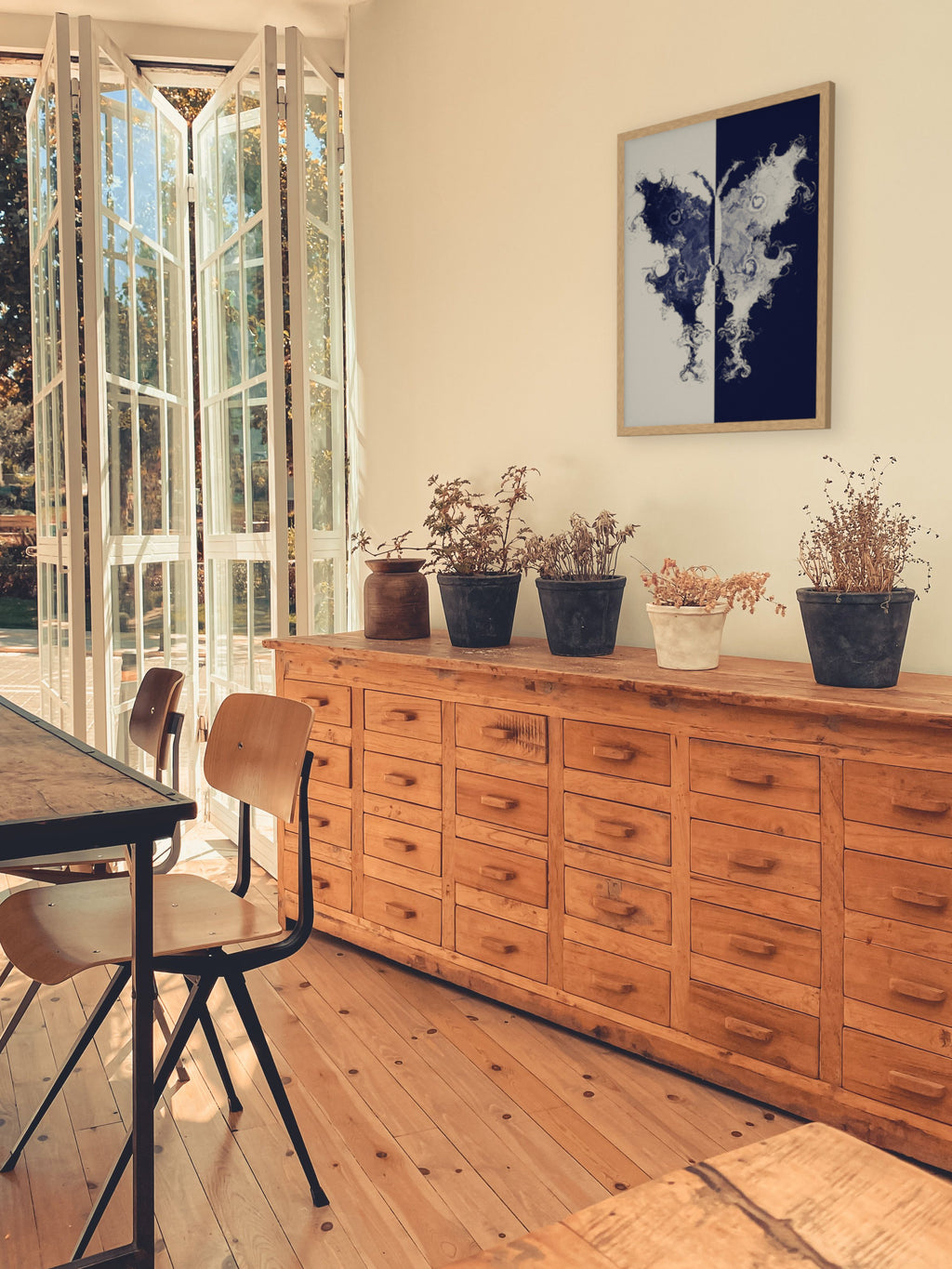 The Fold moth ink blot art print, cream and indigo study wall art, shown above an apothecary chest