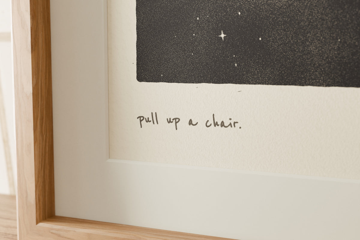 Close-up of the matte archival paper and handwritten caption on the Pull Up a Chair dining room print